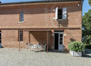 Een gebouw van baksteen met een overdekte patio, een deur en een raam.