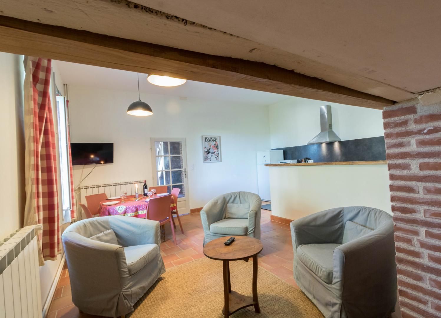 Un salon chaleureux avec deux fauteuils, une petite table ronde et un coin repas avec une table dressée pour deux personnes.