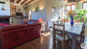 Una sala de estar acogedora con un sofá rojo, una mesa de comedor de madera y una chimenea.