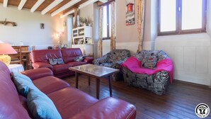 Una sala de estar acogedora con un sofá de cuero rojo, un sillón estampado y una mesa de centro de madera.