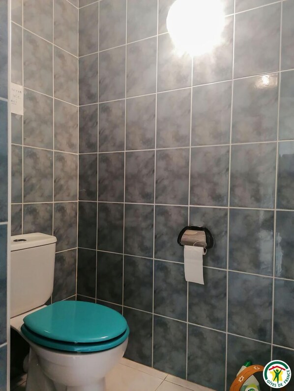 Un baño con inodoro, dispensador de toallas de papel y una pared con diseño de cuadrícula.