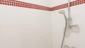 A shower with a handheld showerhead and a wall-mounted faucet.