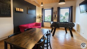 Une pièce chaleureuse avec une table en bois, un canapé rouge et une table de baby-foot.