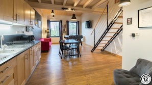 Une cuisine moderne avec des meubles en bois, un coin repas doté d’un canapé rouge et un escalier.