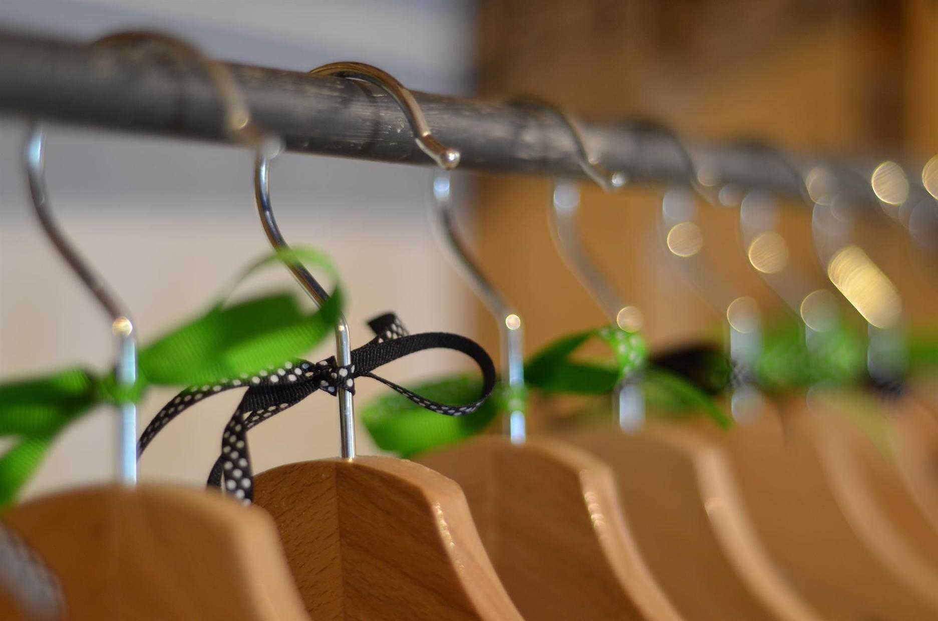 Fileira de suportes para sapatos de madeira com tiras estampadas em preto e branco penduradas em ganchos de metal.