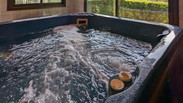 Un jacuzzi con vistas a montañas a través de amplios ventanales.