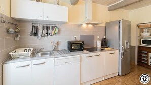 Eine moderne Küche mit weißen Schränken, einem integrierten Geschirrspüler, einem Edelstahlkühlschrank, einer Mikrowelle und einem Elektroherd mit Umluftfunktion.