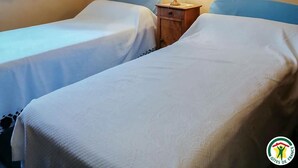 Ein Hotelzimmer mit zwei Einzelbetten, einer Kristallleuchter, einem Fenster mit Vorhängen und gerahmten Bildern an der Wand.