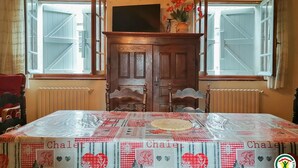 Ein Essbereich mit einem Tisch, der mit einer gemusterten Tischdecke bedeckt ist, einer Holzkabine und einer Chandelier.