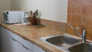 Eine Küche mit Mikrowelle, Kaffeemaschine und Geschirr auf der Arbeitsplatte.