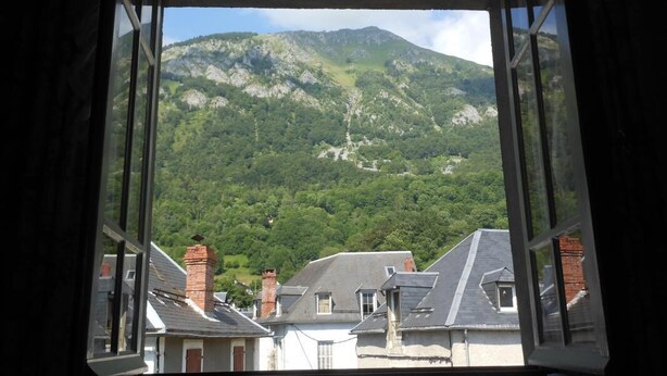 Blick aus einem Fenster auf ein Gebirge mit Gebäuden im Vordergrund.