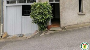 Ein Gebäude mit mehreren Fenstern, einige mit Fensterläden, und einem kleinen Blumentopf im Vorbereich.