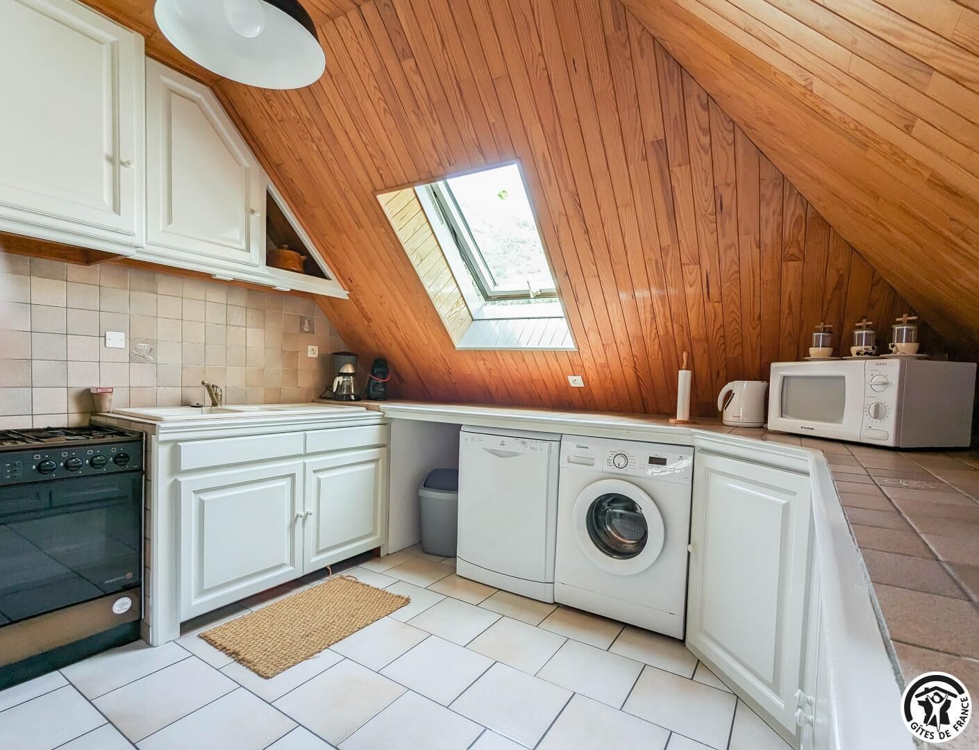 Cocina compacta con tragaluz, estufa, lavadora y microondas.