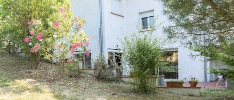 Un bâtiment blanc doté d’un toit plat, entouré d’arbres et d’arbustes.