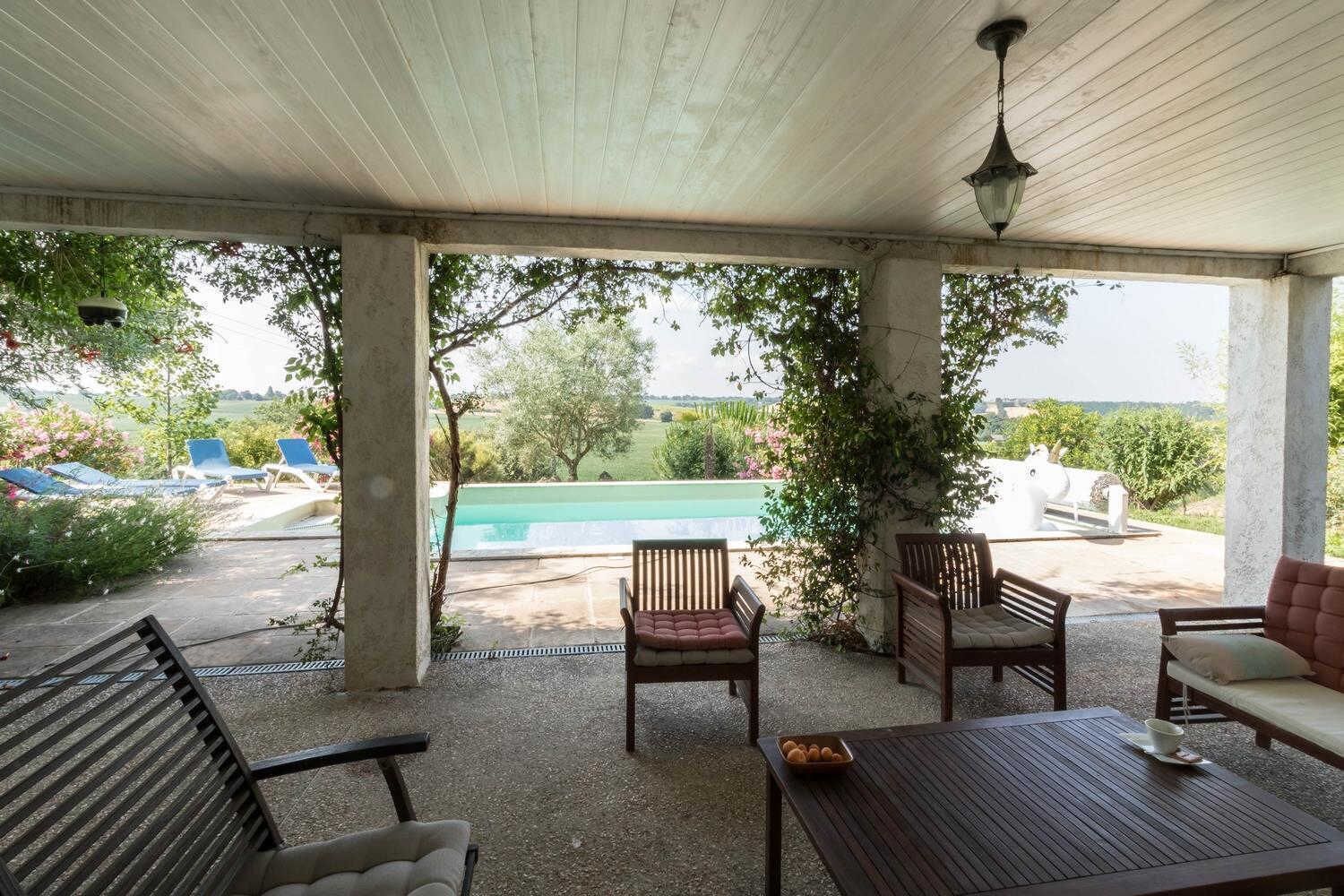 An outdoor patio with a pool, lounge chairs, and a table.