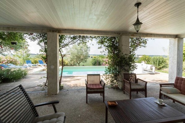 An outdoor patio with a pool, lounge chairs, and a table.