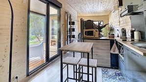 A modern kitchen with wooden cabinetry, a built-in oven, and a large window overlooking a garden. - L'Oustal de la Mane d'Auta (AYGUESVIVES)