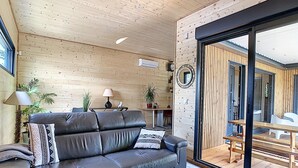 A modern living room with a leather sofa, a round mirror, and a dining area with a table and chairs. - L'Oustal de la Mane d'Auta (AYGUESVIVES)