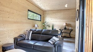 A cozy room with a leather sofa, two lamps, a small table, and a window with a view of greenery. - L'Oustal de la Mane d'Auta (AYGUESVIVES)