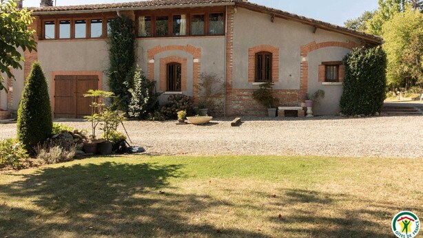 A two-story house with a brick facade, a gravel driveway, and a well-maintained garden with various plants and a lawn. - Borde Basse - L'HERM - Gîte (LHERM)