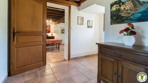 A hallway with a wooden door, a dining area with a table and chairs, and a painting on the wall. - Borde Basse - L'HERM - Gîte (LHERM)