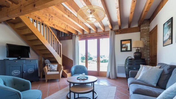 A living room with a staircase, a television, a sofa, and a table with candles. - La Ferme de Menoun - Thil (Thil)