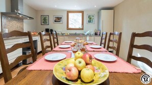 A dining area with a table set for six, surrounded by wooden chairs. A large bowl of fruit is placed on the table, and there are framed pictures on the wall. - Vignes - Saint-Léon - Gîte (Saint-Léon)