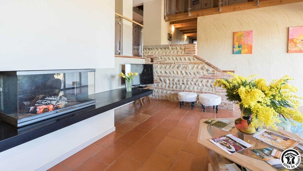 A modern interior with a fireplace, a staircase, and a dining area with a table and chairs. - Vignes - Saint-Léon - Gîte (Saint-Léon)