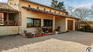 A two-story house with a patio area, a garage, and a gravel driveway. - Vignes - Saint-Léon - Gîte (Saint-Léon)