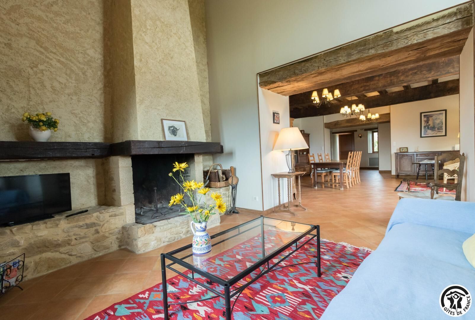 Amplia sala de estar con chimenea de piedra, un televisor de pantalla plana y una mesa de centro de vidrio.