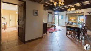 A spacious dining area with a large wooden table and chairs, a chandelier, and a view of the outdoors through a glass door. - Picanas - Boussan - Gîte (Boussan)