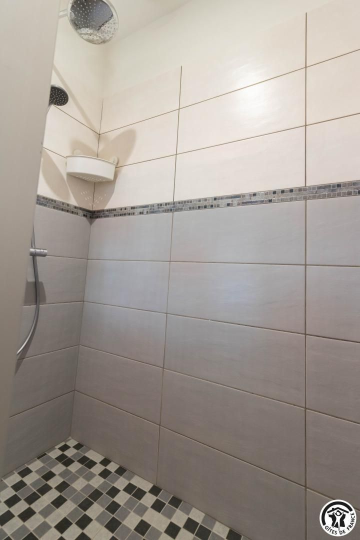 Un espace douche avec des murs carrelés et un sol à carreaux.