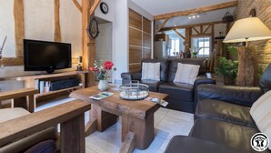 Un salon chaleureux avec un meuble TV en bois, un canapé en cuir et une table basse.