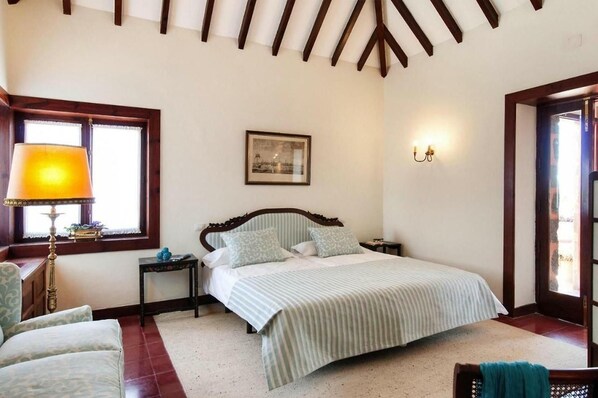 A bedroom with a bed, a nightstand, a lamp, a framed picture, and a window with curtains.