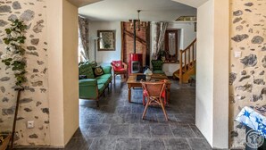 A cozy living room with a fireplace, green sofa, and a dining table. - Le Castel Vert - Valcabrère (Valcabrère)