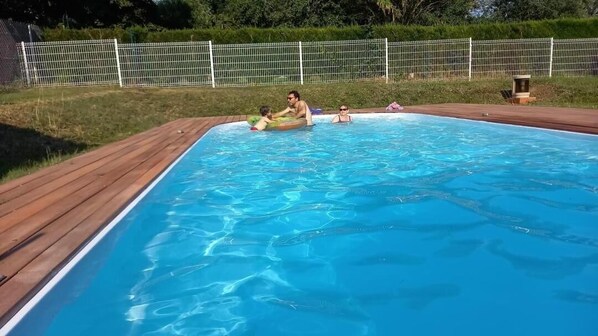 A rectangular swimming pool with a wooden deck surrounding it.