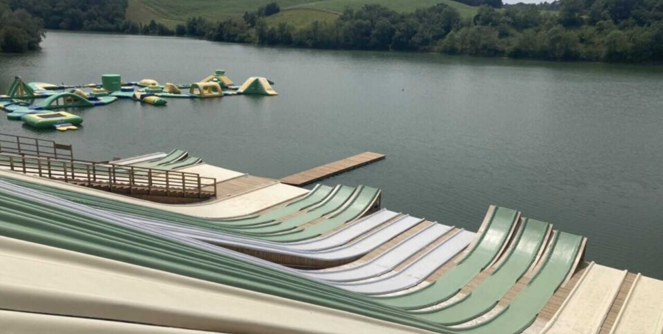 A series of green and white water slides leading into a lake.