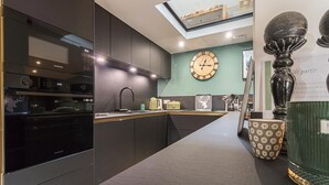 A modern kitchen with a built-in oven, a clock on the wall, and a skylight above the counter. - Chalet le René-Sens - BOUTX (COULEDOUX)