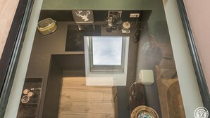 A room with a skylight, a small table with a decorative item, a wall-mounted radio, and a window. - Chalet le René-Sens - BOUTX (COULEDOUX)