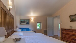Une chambre d’hôtel avec deux lits, une armoire en bois, un tableau et une fenêtre donnant sur un beau paysage.
