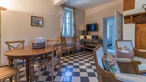Un coin repas avec un sol à carreaux, une table en bois et des chaises en osier.