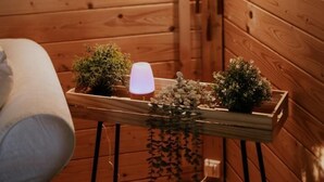 Un coin douillet aux murs en bois, une petite table agrémentée de plantes et d’une lampe, et un tableau encadré accroché au mur.