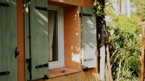 Un bâtiment rustique doté d’une fenêtre et d’une porte, entouré de verdure et d’un lampadaire.