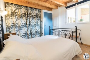 Een slaapkamer met een bed, nachtkastje, lamp, raam en deur.