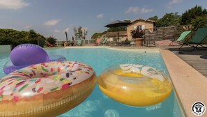 A swimming pool with inflatable rings and lounge chairs.