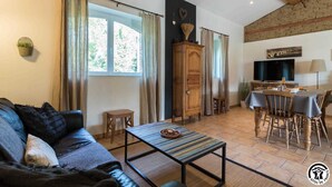 A cozy living room with a sofa, a coffee table, a dining area with a table and chairs, and a TV.