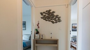 A hallway with a wooden console table, a wall-mounted decorative fish sculpture, and a framed picture on the wall.