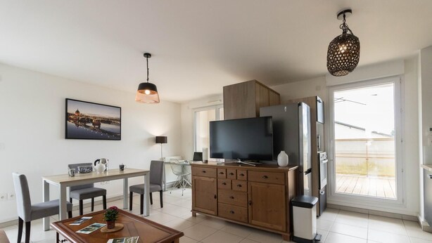 A modern living room with a dining area, a TV, and a large window.