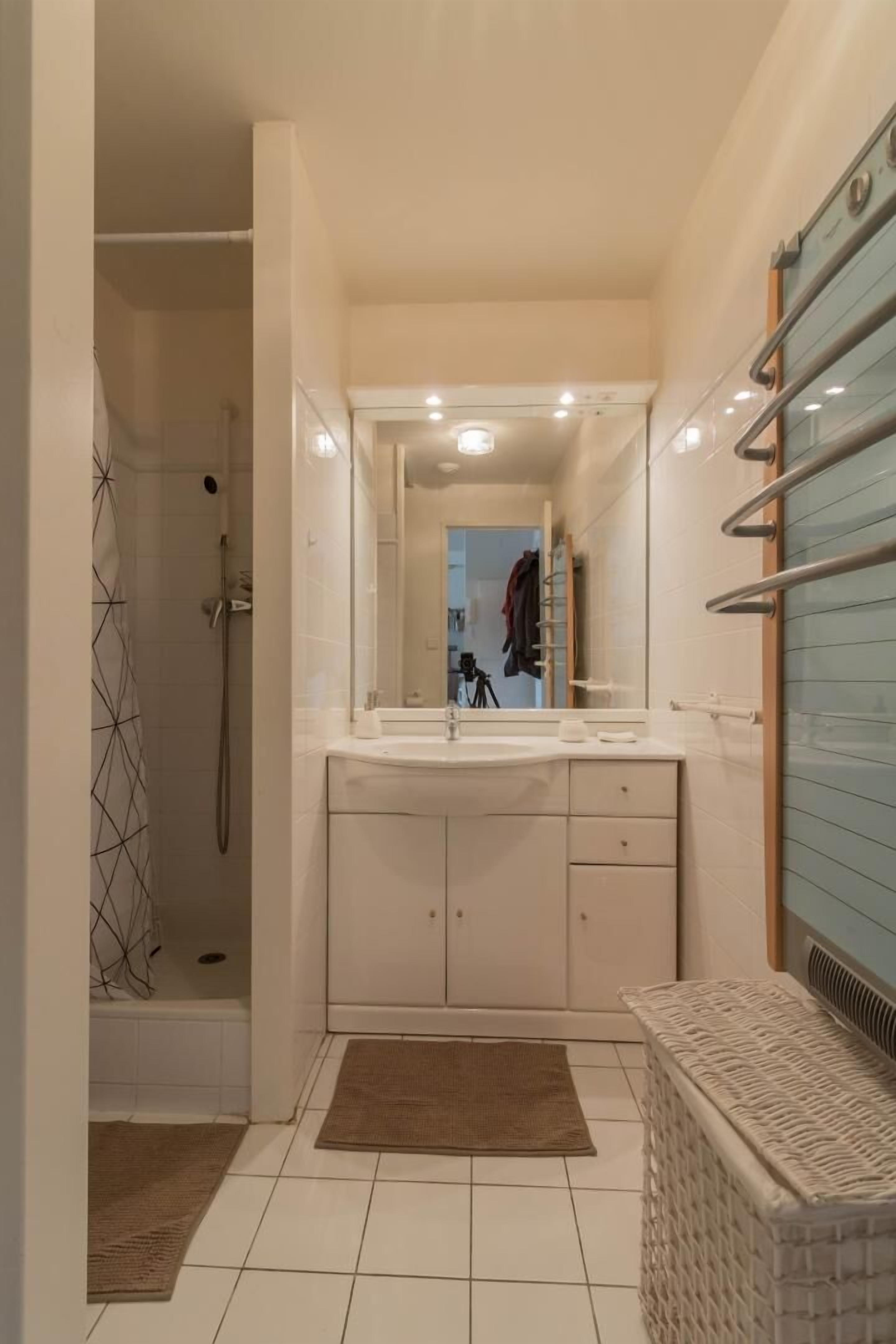 A modern bathroom with a walk-in shower, a large mirror, and a white sink with a vanity.