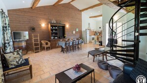 Un salón espacioso con techo de madera, un comedor y una escalera moderna.